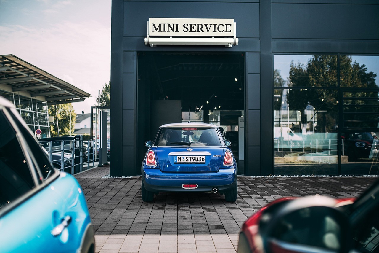 Вид сзади на MINI Hatch в цвете Electric Blue Metallic, въезжающий в сервисный центр MINI.